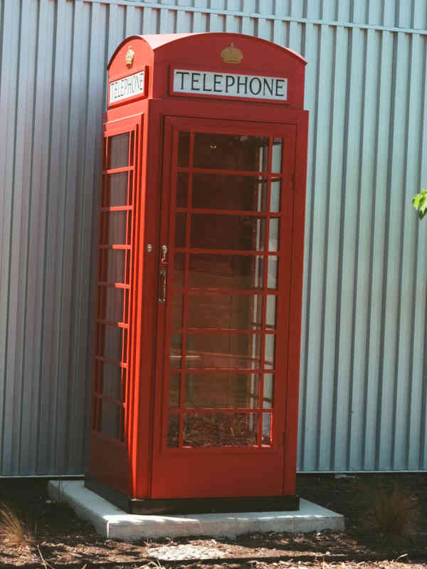 The red Wind Phone Booth standing on a concrete pad beside the building at The Front Porch